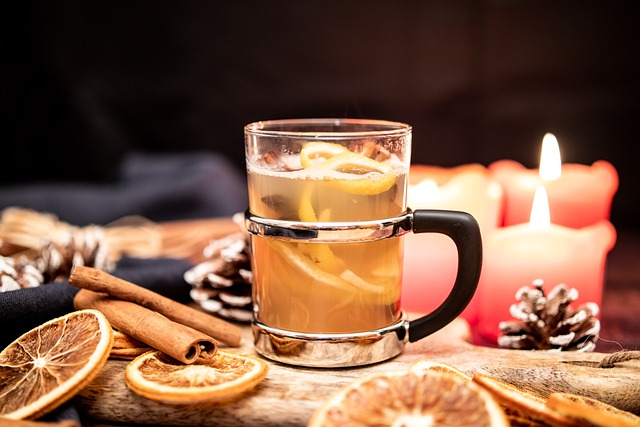 Tea in a glass mug on a table with orange slices and cinnamon sticks.